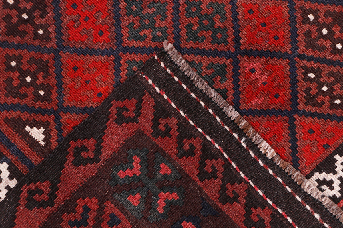 Kilim rug corner with red and black squares, diamonds, and white accent trim