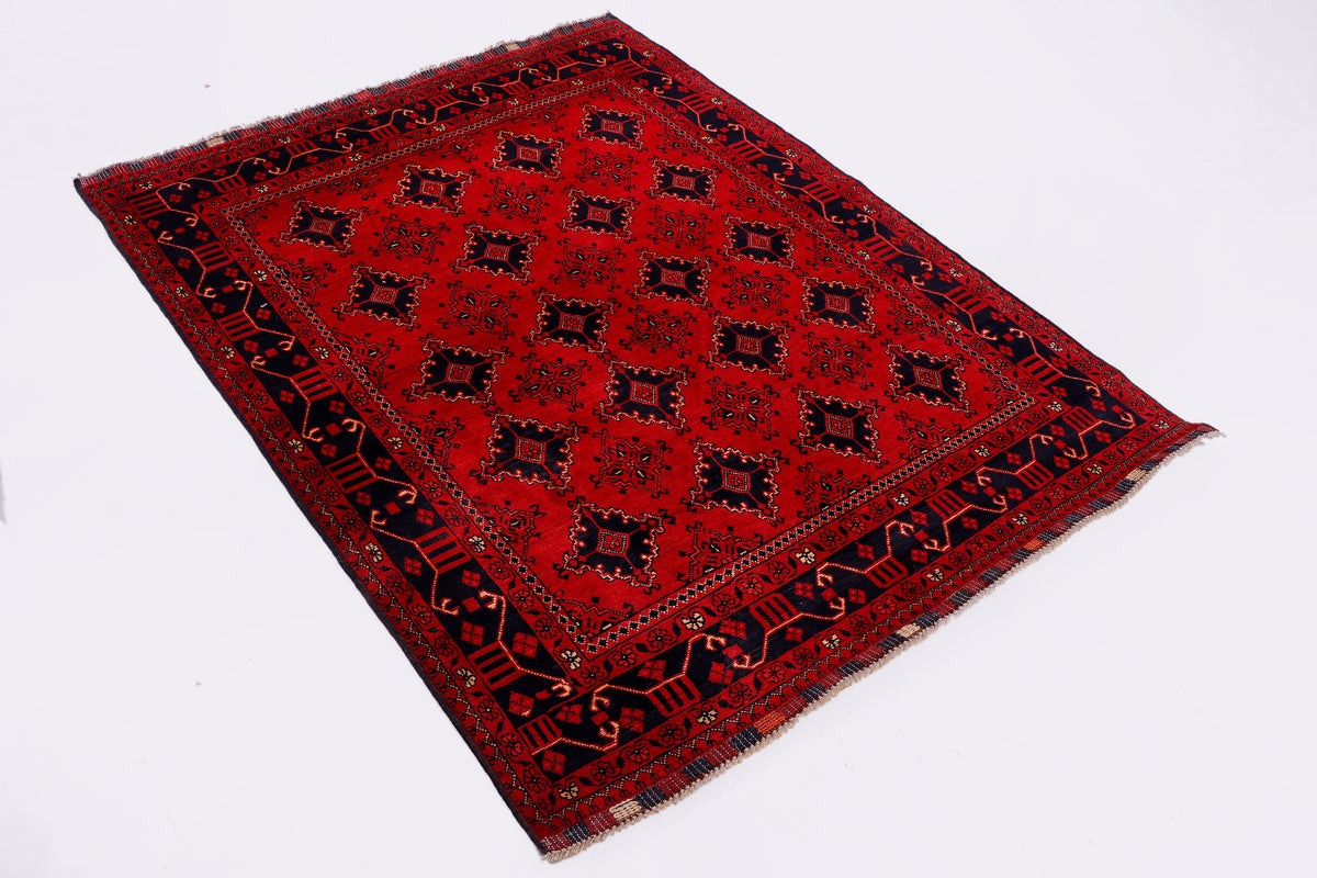 Red area rug with detailed geometric motif and dark border, angled view