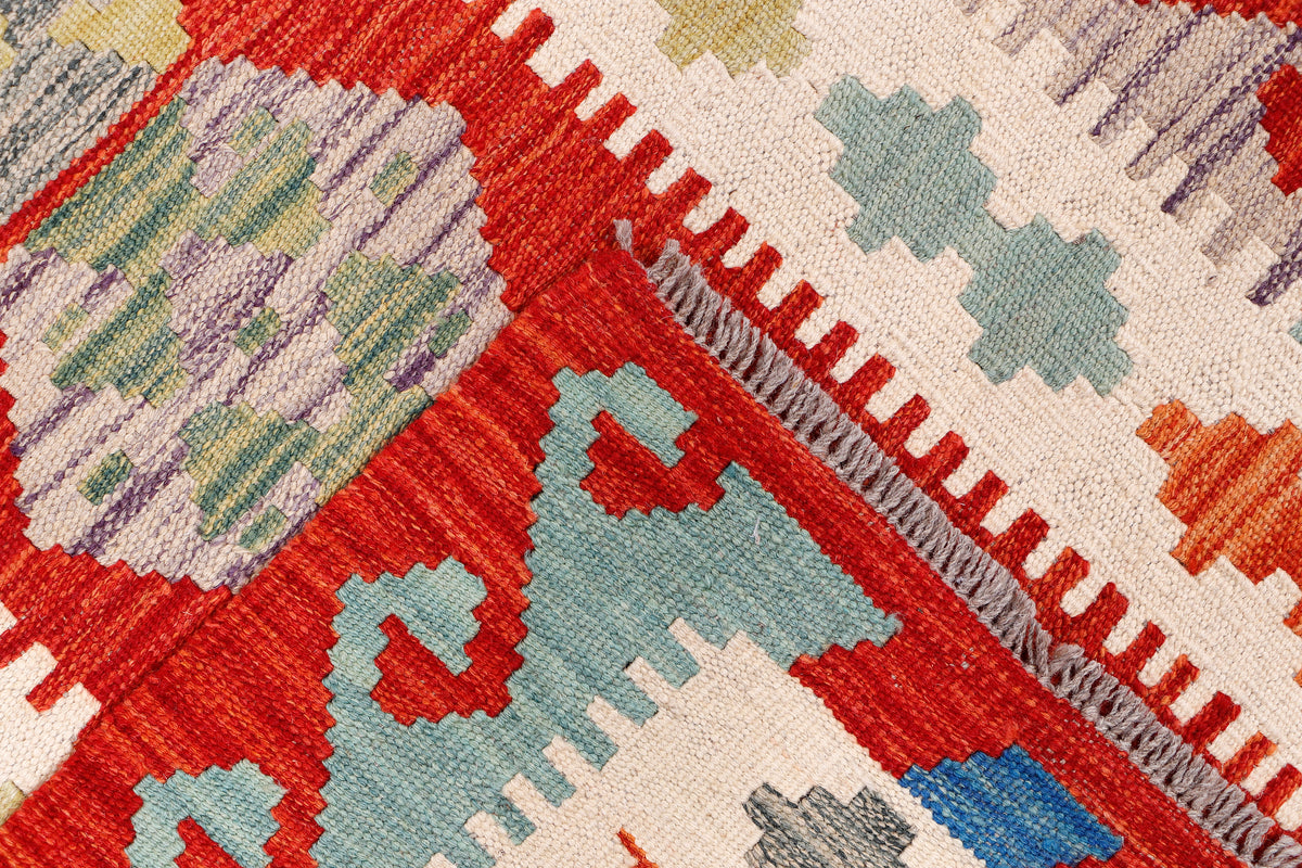 Kilim runner rug close-up with red, cream, and blue geometric border and center motifs