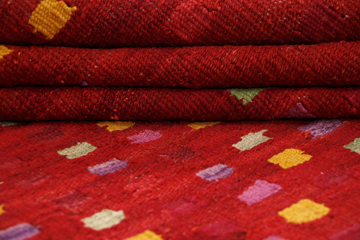 Crimson mosaic red kilim rug texture with folded edge and multicolor motifs