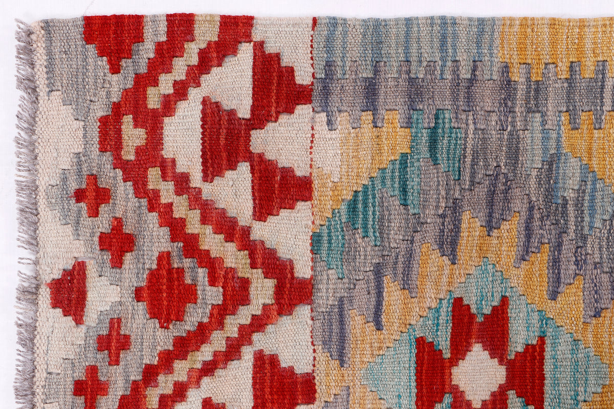 Close-up of grey kilim rug weaving with red and blue geometric blocks