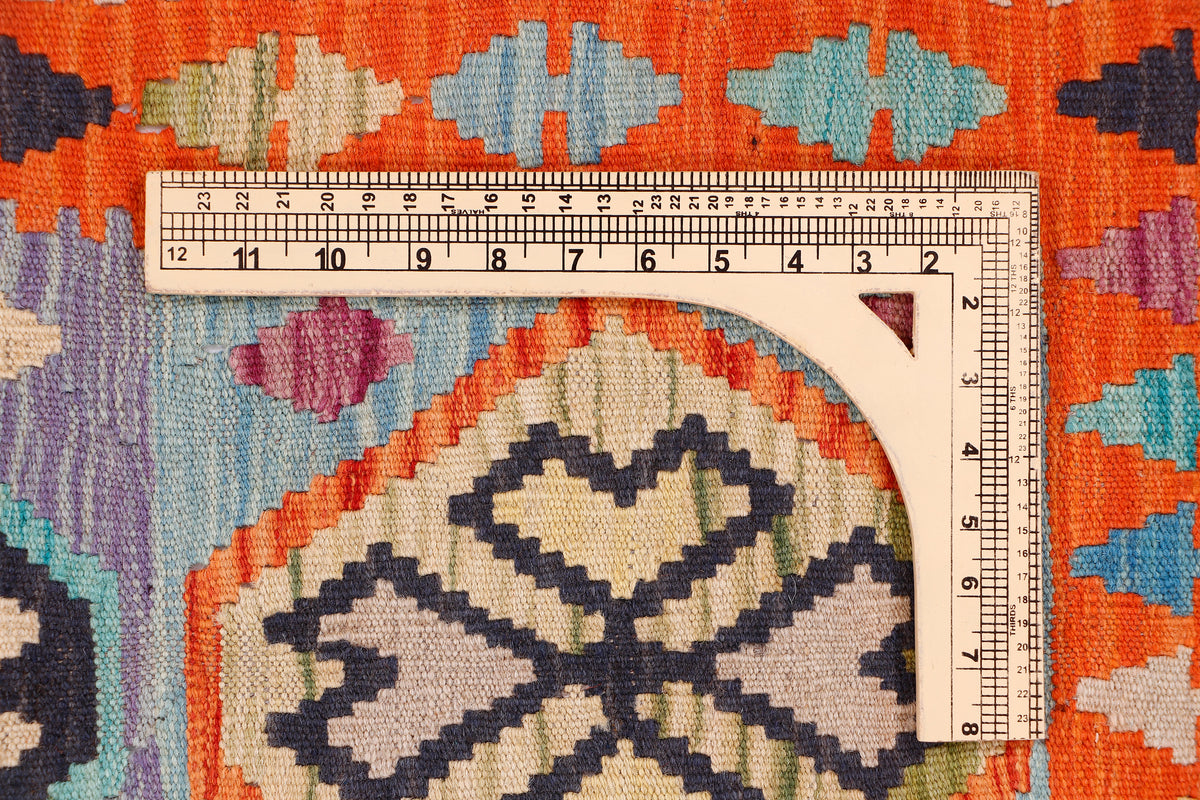 Kilim rug section with measuring tape and geometric motifs in orange and blue