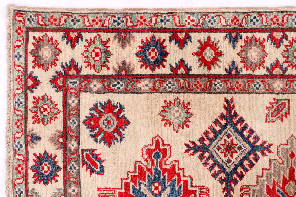 Kazak red rug corner detail with multicolor geometric motifs and decorative border