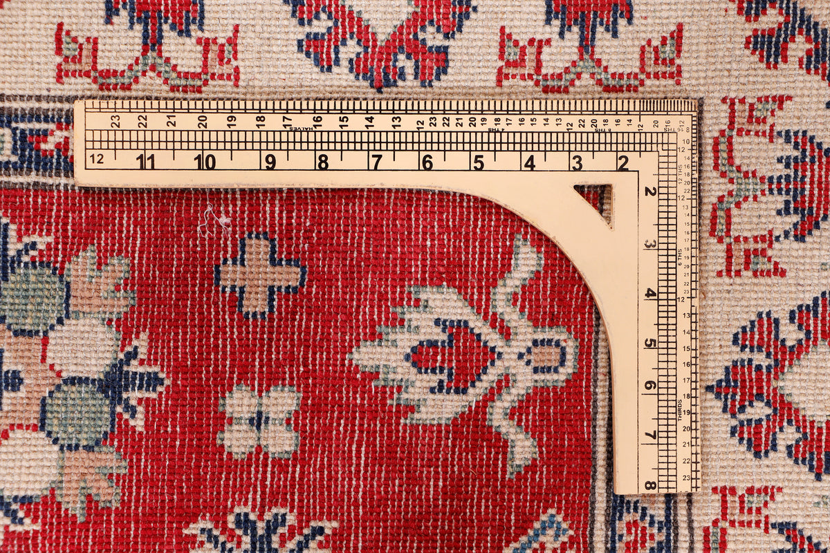 Red rug corner with blue and cream geometric border, close-up texture with tape