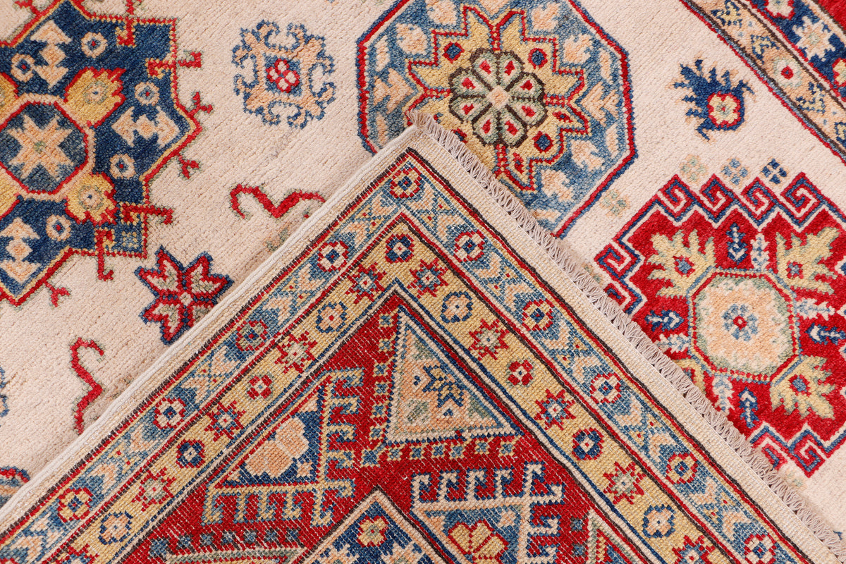Cream and red rug with blue diamond accents and intricate geometric border detail