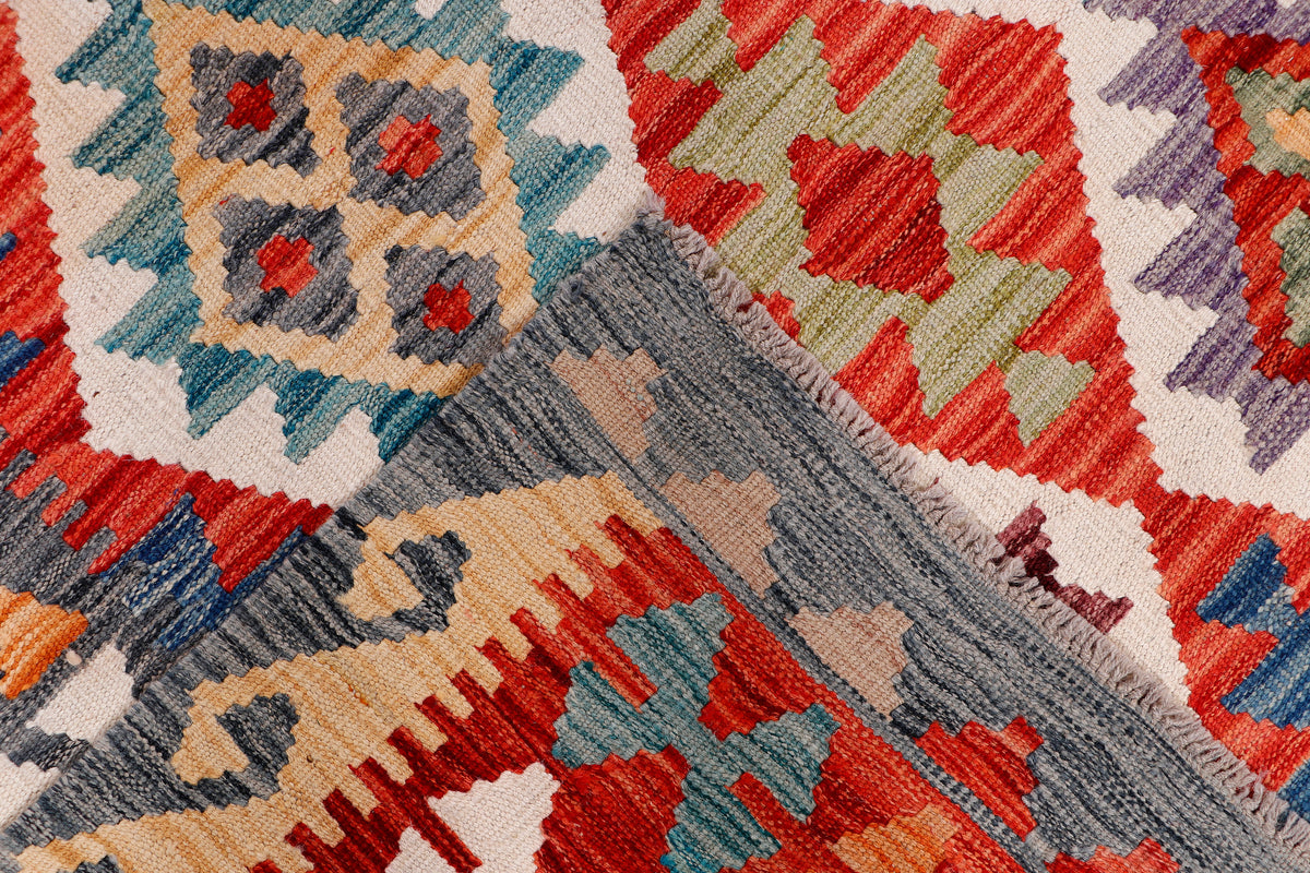 Kilim rug texture detail with woven gray, red, green, and cream geometric shapes