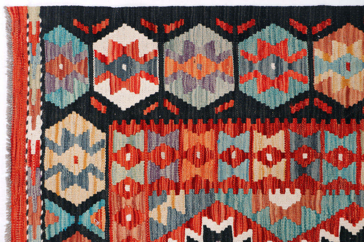Kilim rug section with red, teal, black, and cream diamond motifs and striped border