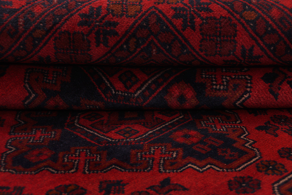 Close-up of red and dark geometric rug pattern with visible textured pile
