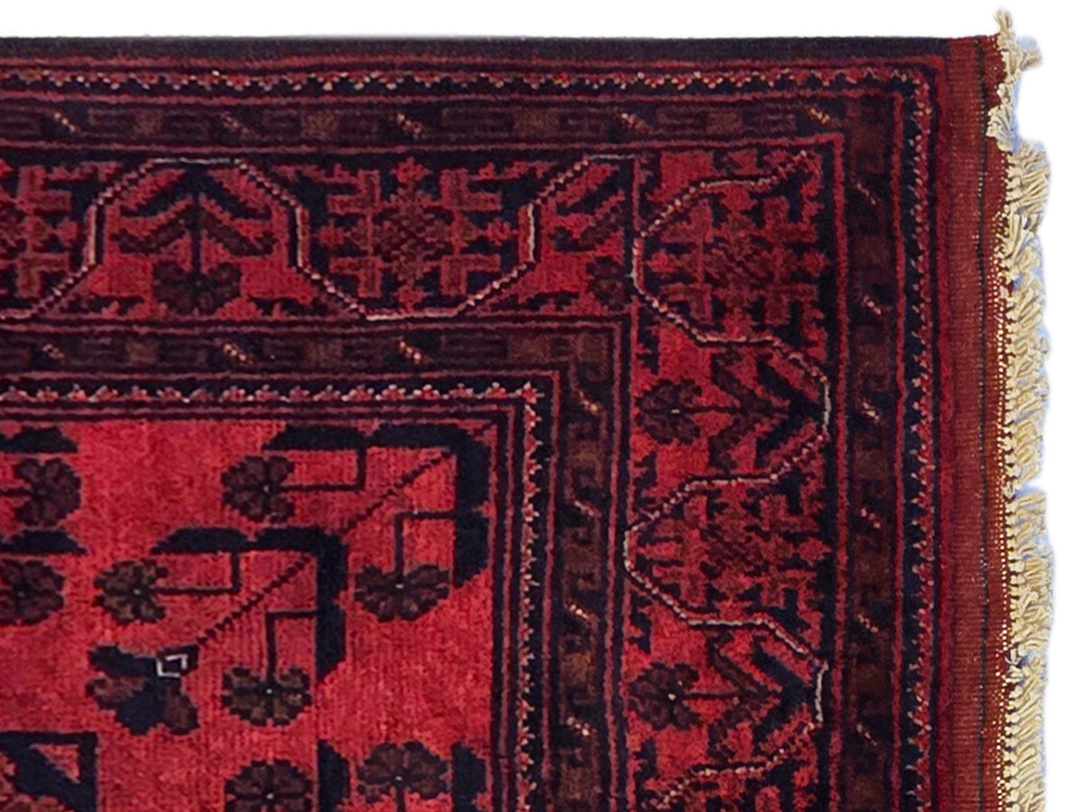 Close-up of Khanmohamad rug texture with deep red panels and dark geometric patterns.