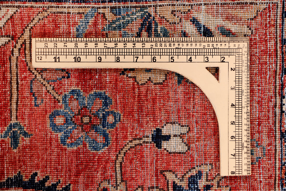 Red patterned rug with measuring tape along the edge and floral medallions