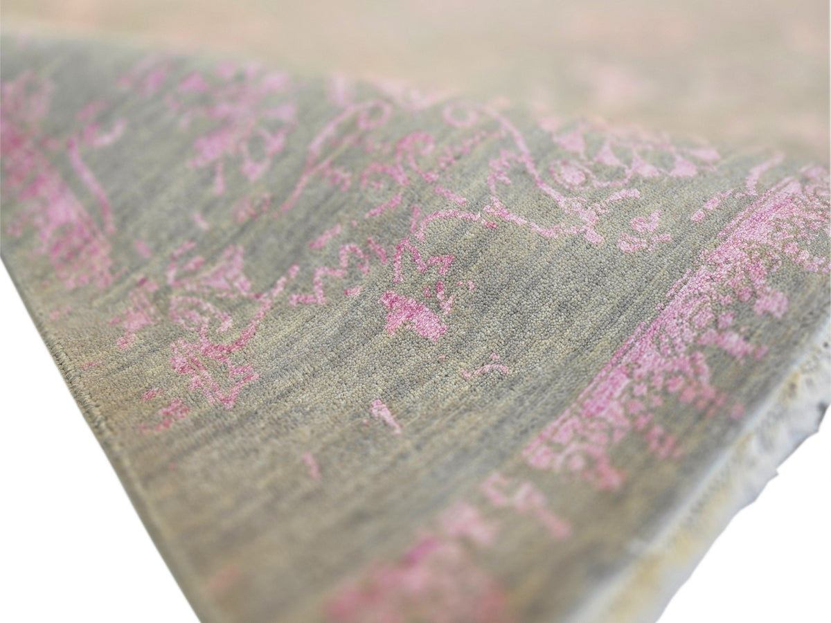 Close-up of modern rug corner: gray pile with bright pink floral motifs