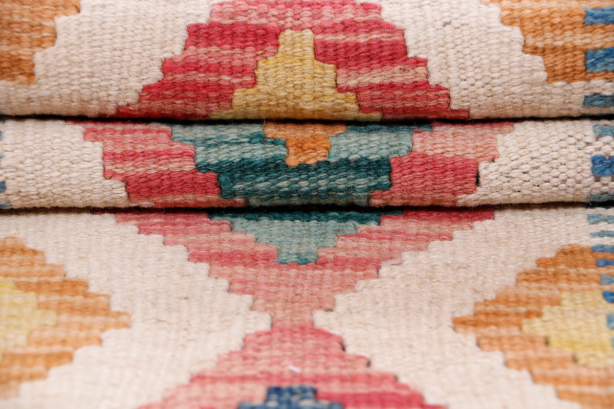 Kilim rug close-up showing worn texture and multicolor cross-stitch style pattern