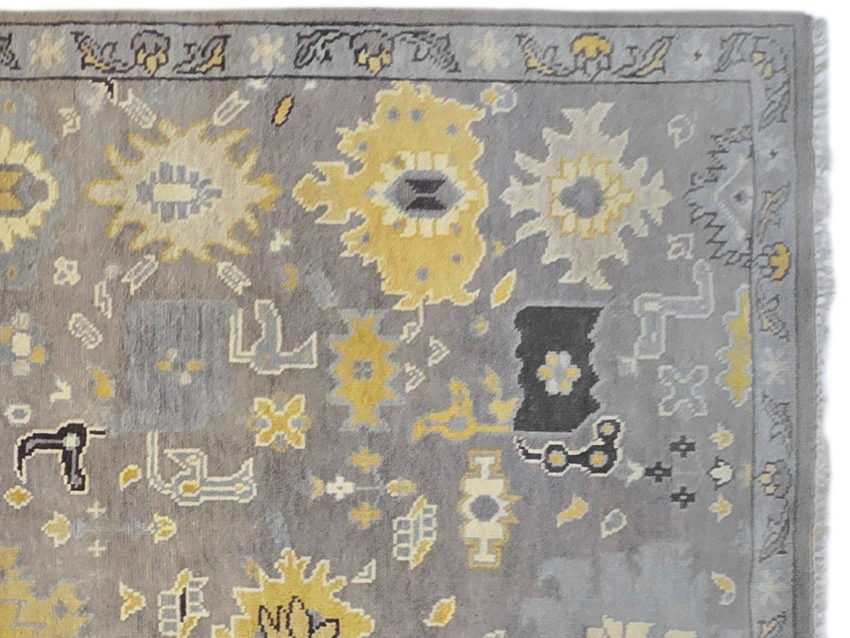 Oushak rug close-up: gray field with yellow and dark geometric floral motifs.