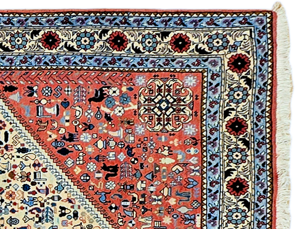 Rug border close-up with red floral motifs, blue vine lines, cream background and fringe