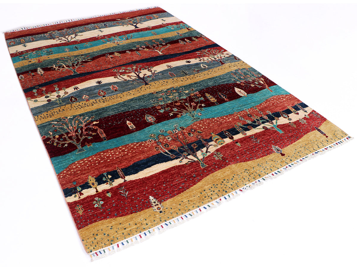 Ariana Gabbeh rug angled view with red, teal, and tan panels and tree motifs.