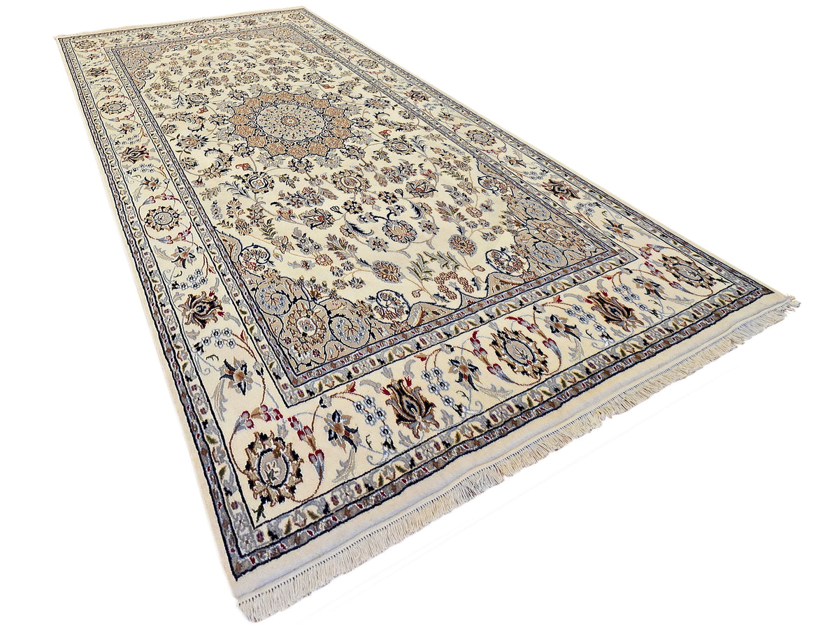 Cream ivory area rug with blue ornate medallion and floral corner accents, fringed edges.