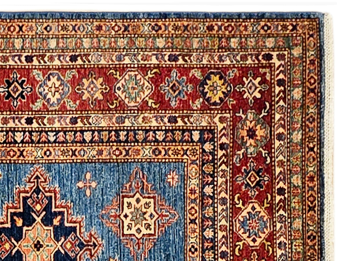 Close-up of geometric blue, red, and beige rug pattern with a central medallion.