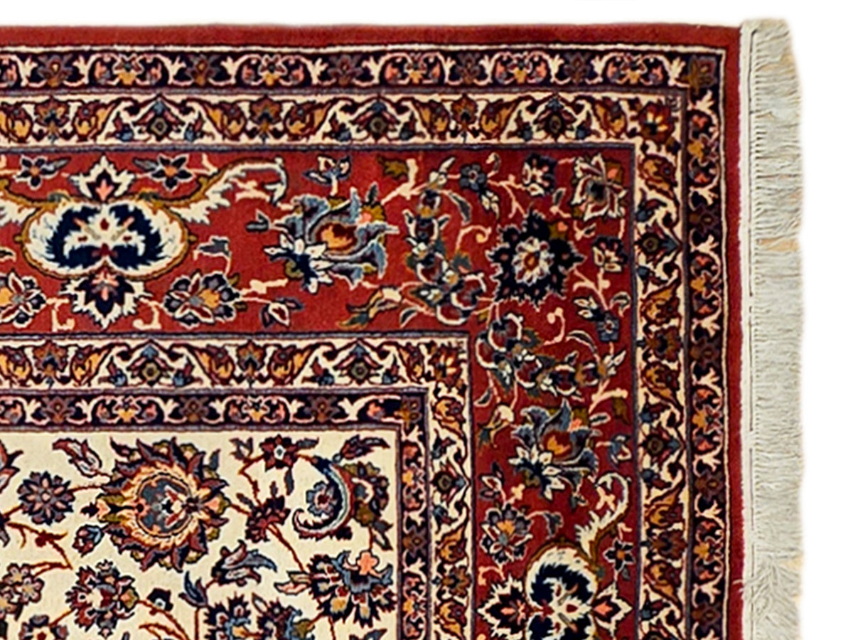 Close-up of red floral rug border with cream panels and visible fringe on edge