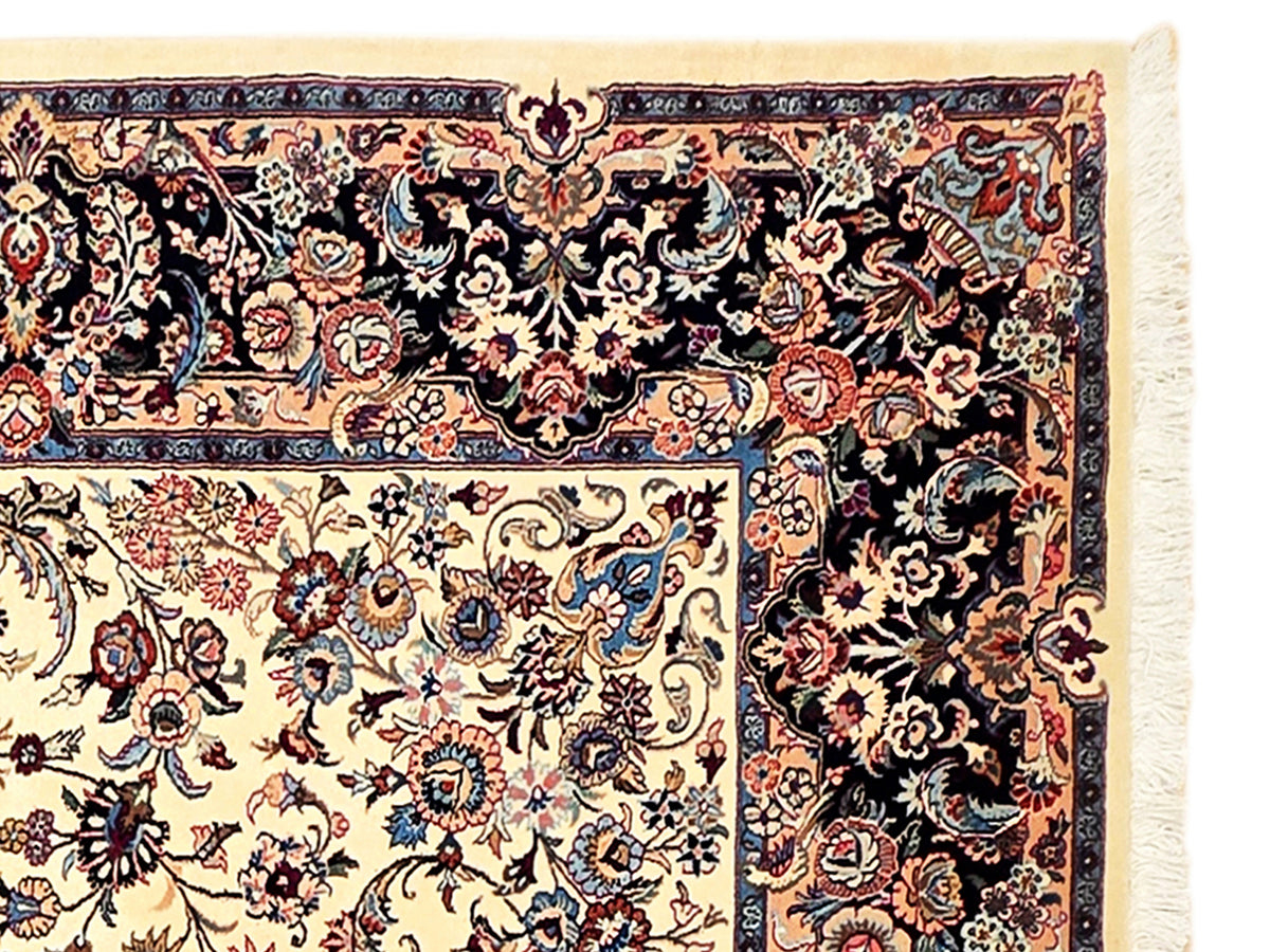 Rug border detail with dark navy ornament, cream floral panel, and fringe along the edge