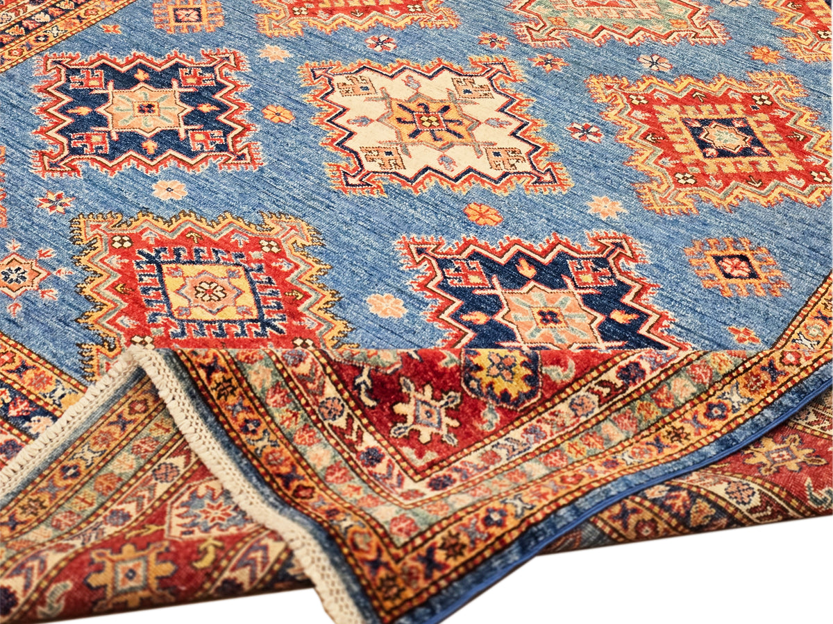 Close-up of blue rug field with orange, red, and cream star and diamond motifs.