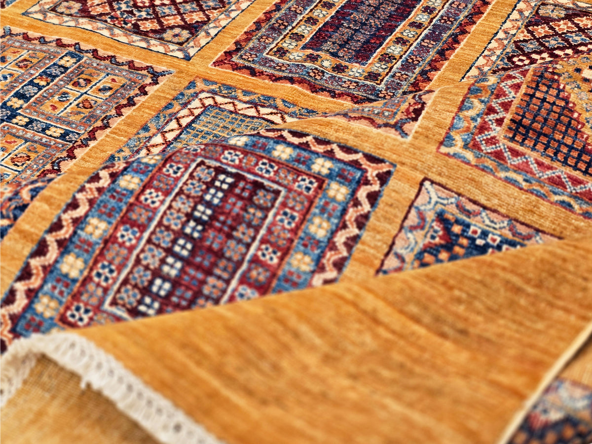 Woven area rug with warm golden ground, blue and red geometric panels, and fringed edge detail