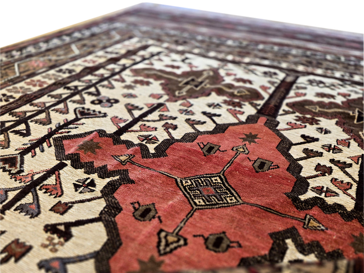 Soumak rug close-up with red center medallion and geometric border in cream and dark brown