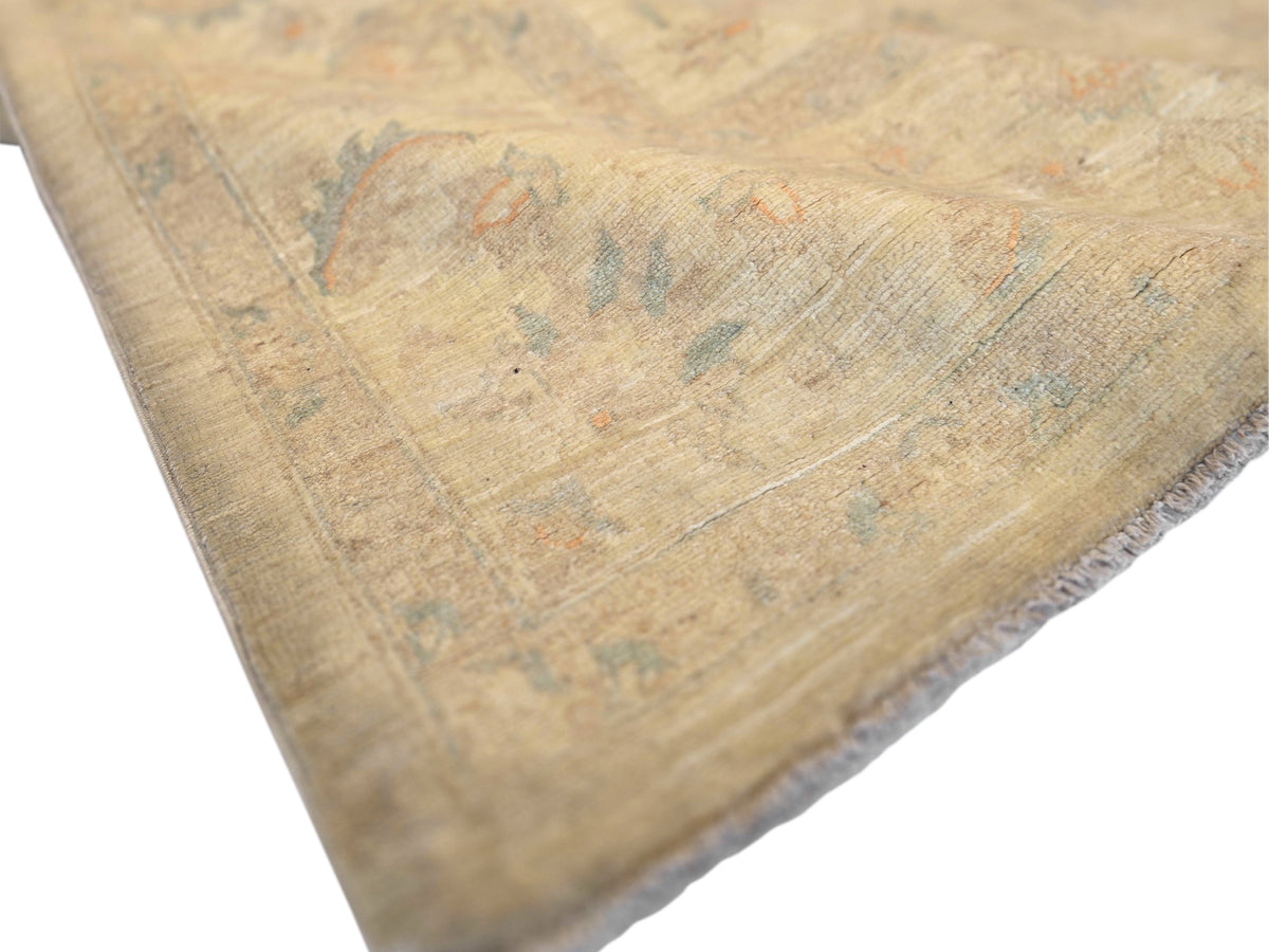 Beige rug detail with worn abstract motifs in blue and orange-gray threads