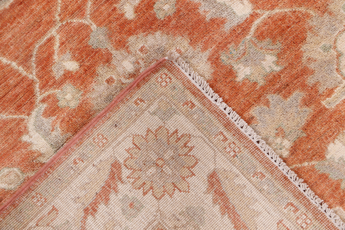 Corner of terracotta and cream patterned rug with stitched edge and detail motif.