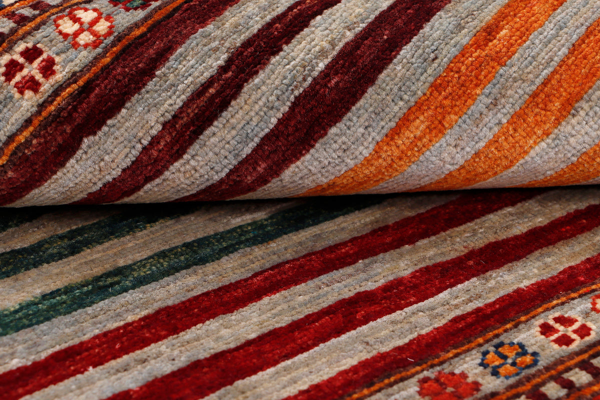 Close-up of striped woven rug in red, orange, green, and cream with low pile