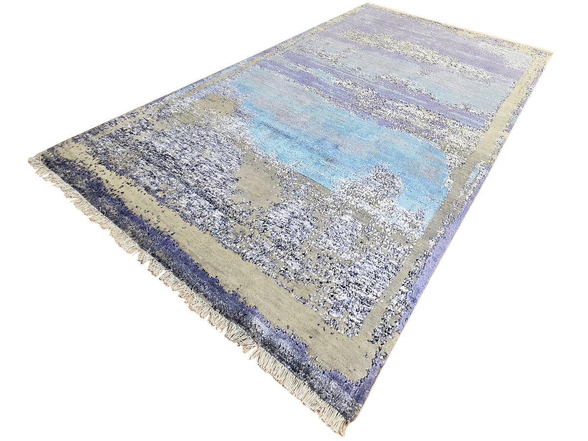 Abstract area rug angled view in blue, beige, and violet with short fringed edges