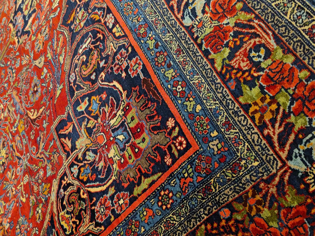 Detail view of red patterned rug with blue lines, multicolor motifs, and floral accents