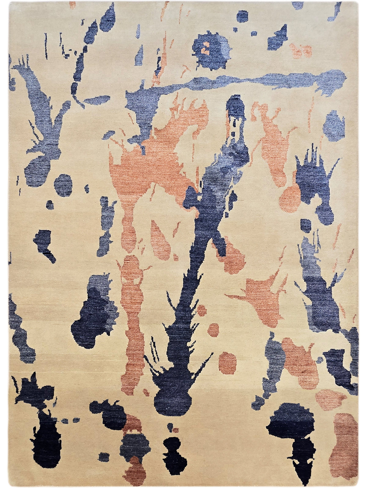 Beige abstract area rug with blue and rust splatter patterns