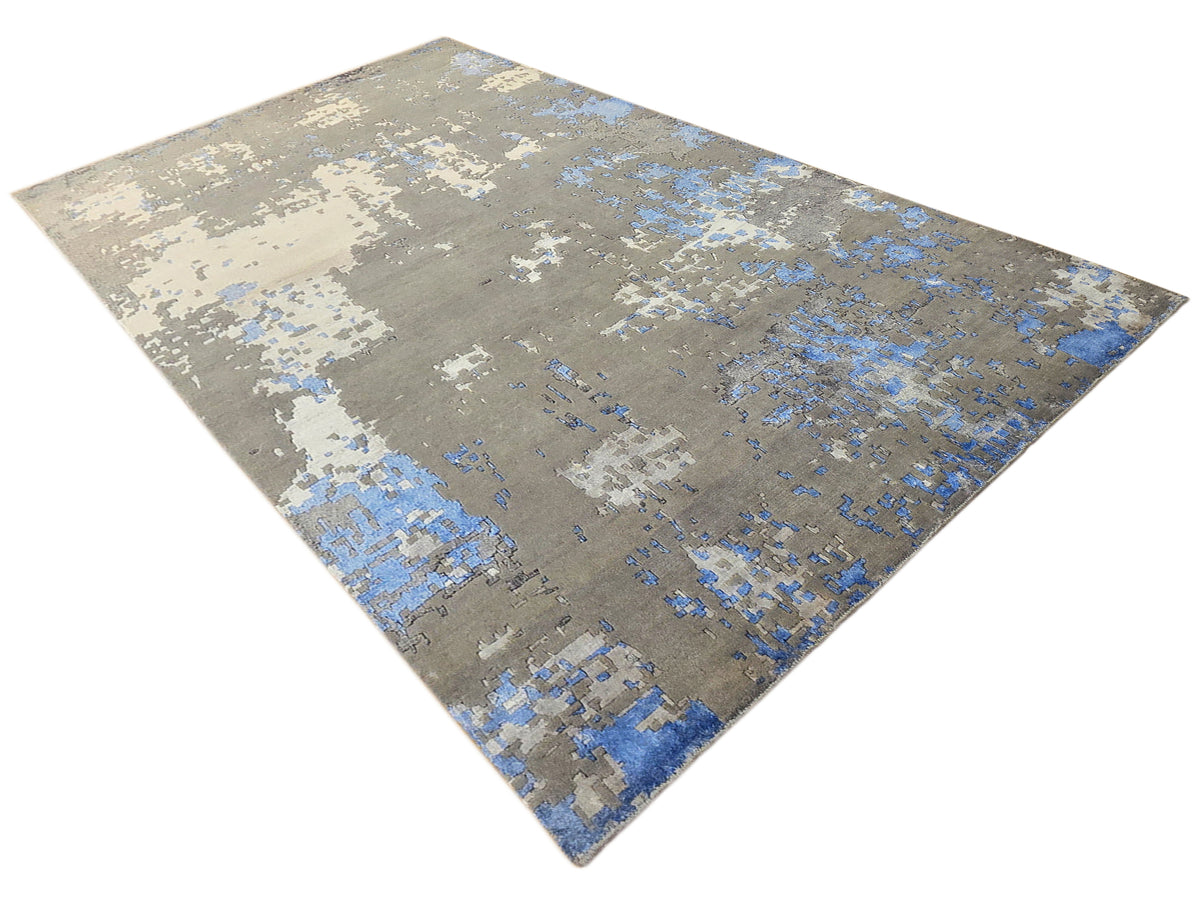 Blue and gray abstract distressed rug with white speckled pattern, corner view