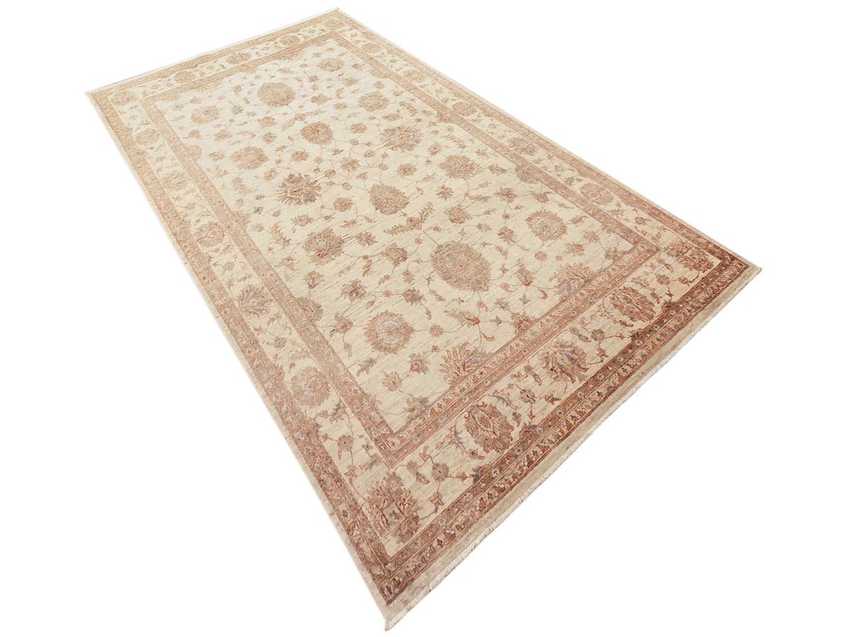 Beige-and-cream rug with rust floral patterns and diamond border, angled view.