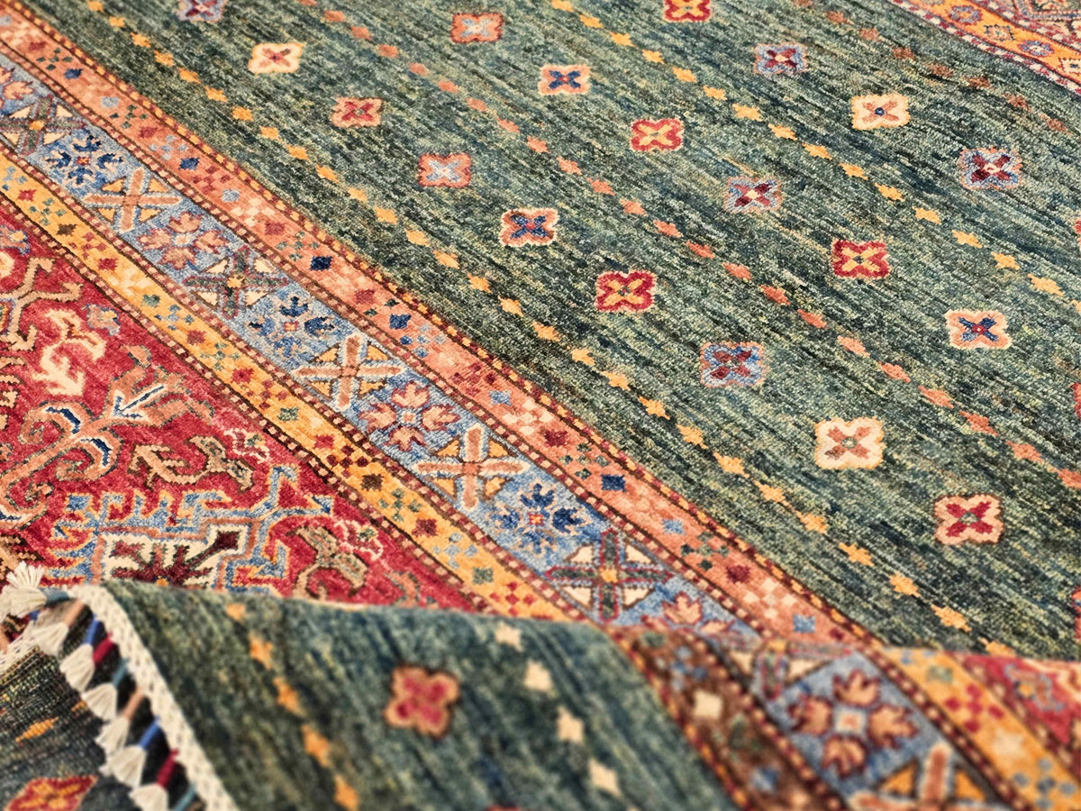 Close-up of multicolor rug pattern with green field, red medallions, and blue bands
