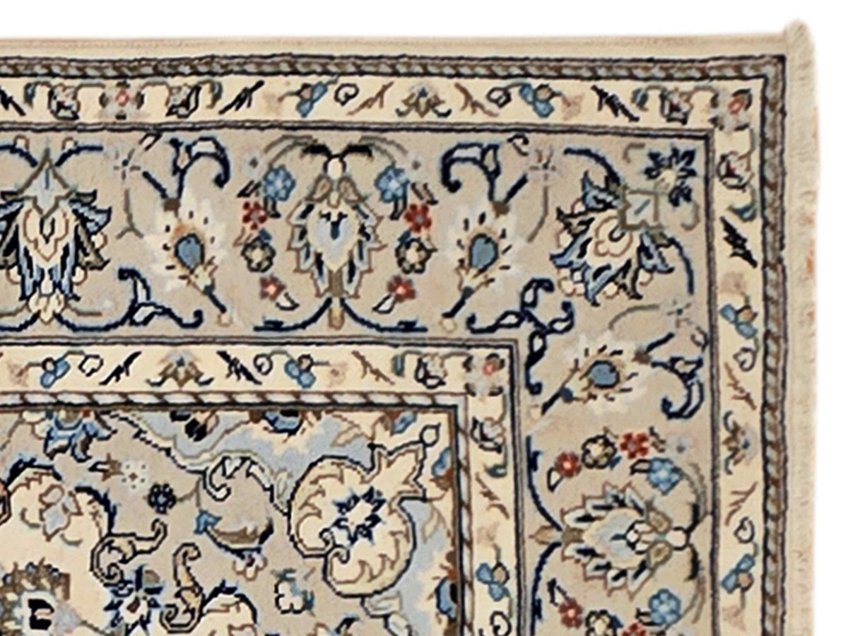 Kashan-style rug close-up with blue vine and floral motifs on cream ground