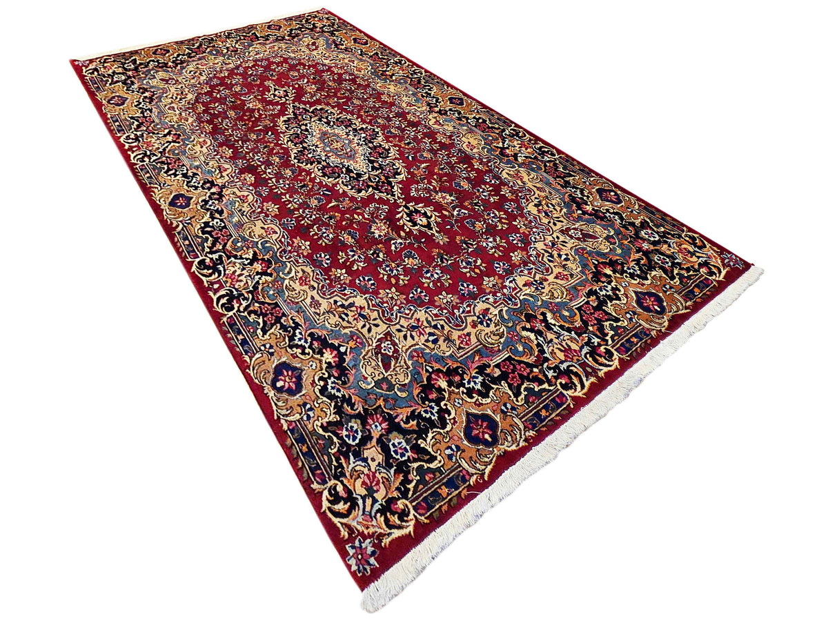 Decorative red rug with intricate floral pattern, medallion center, angled view