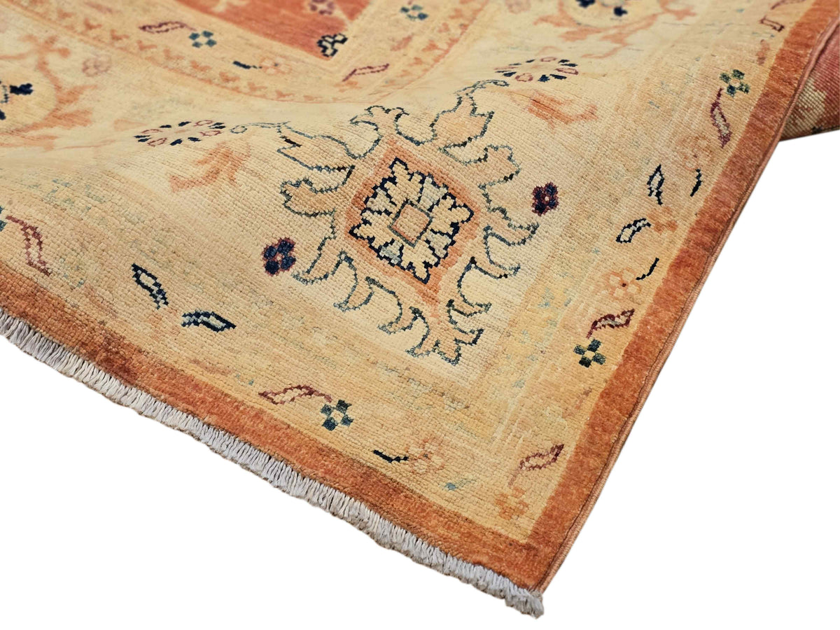 Corner detail of terracotta area rug with geometric pattern and fringed edge