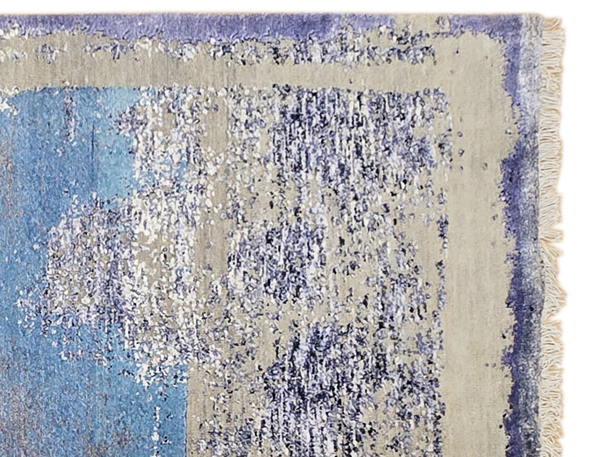 Abstract rug detail in light blue, cream, and dark violet with speckled texture
