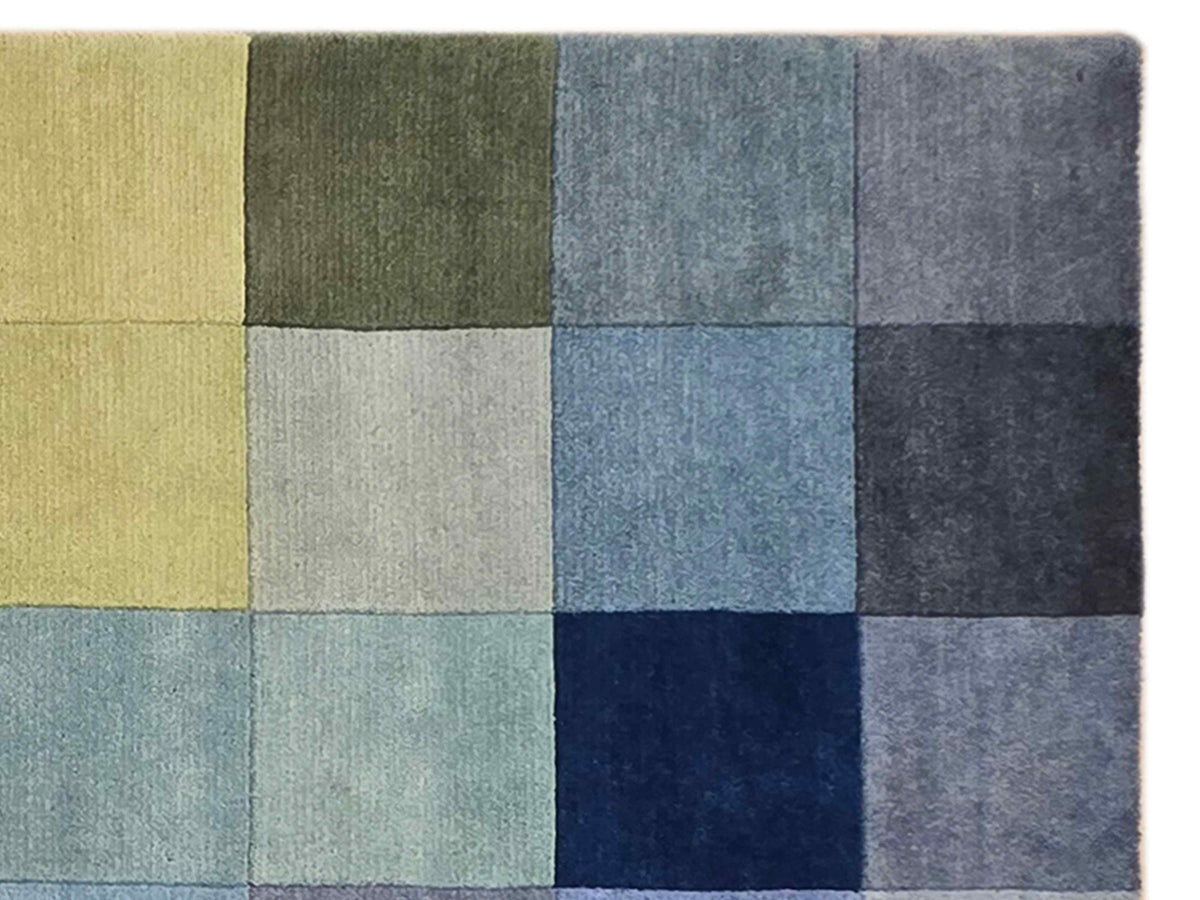 Geometric square-block rug close-up in gray, green, blue, and pale yellow