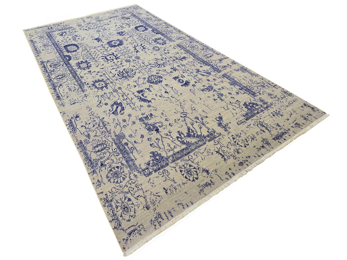 Beige and blue patterned area rug with distressed look and border, diagonal view.