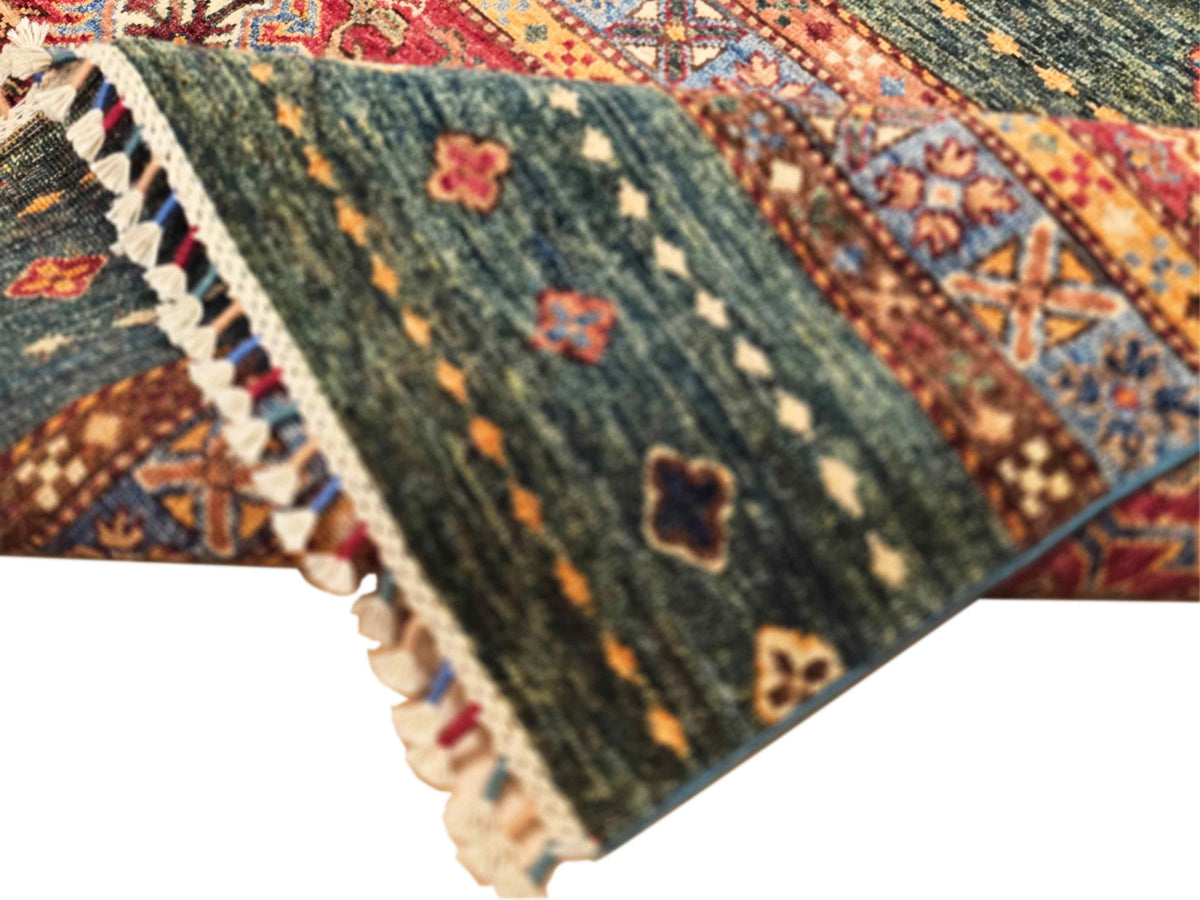 Rug corner detail with cream fringe and dark green ground plus red and orange motifs