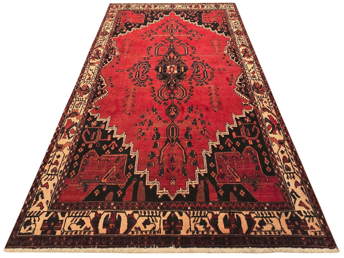 Red area rug with central arch medallion and zigzag border in black and beige