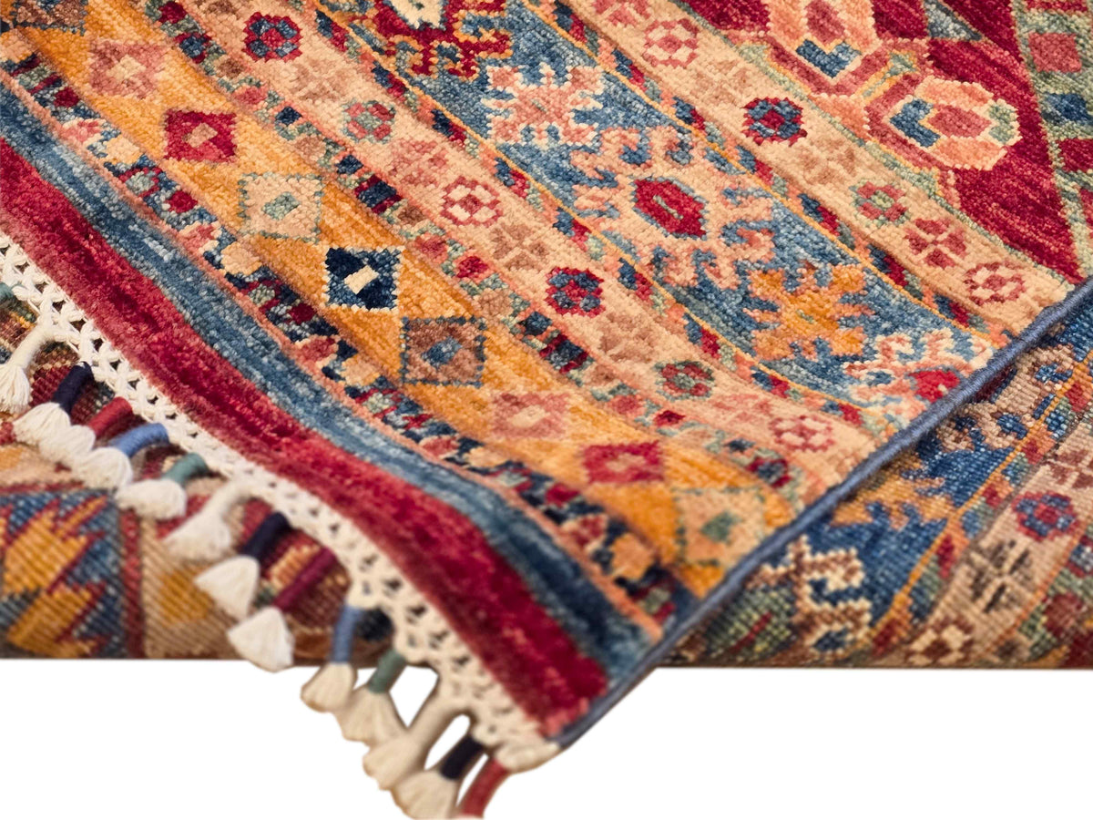 Khorjin-style rug corner close-up with geometric border and cream tassels along edge.