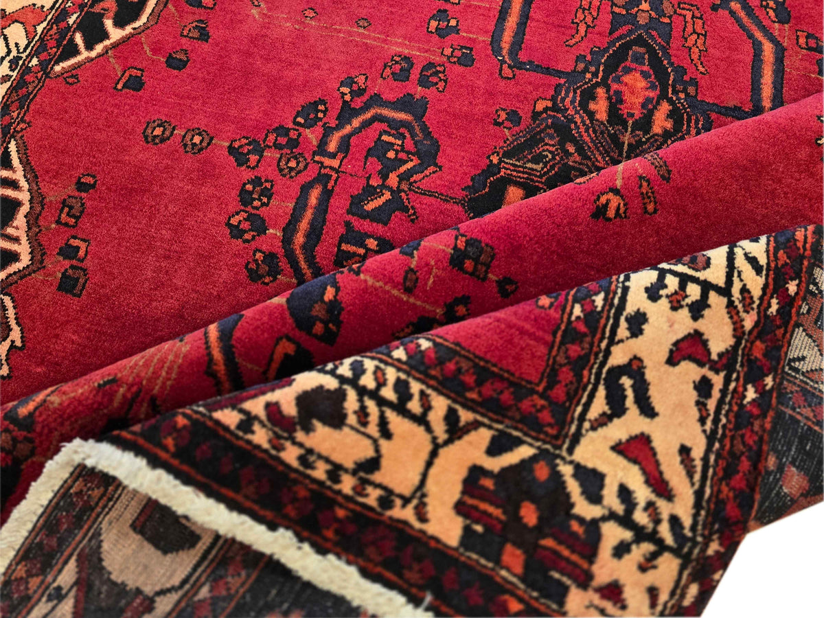 Red rug close-up with swirling motifs and cream accents over black-and-beige panels