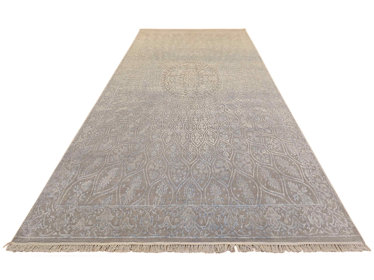 Triangular view of light blue-gray patterned area rug with fringed ends.
