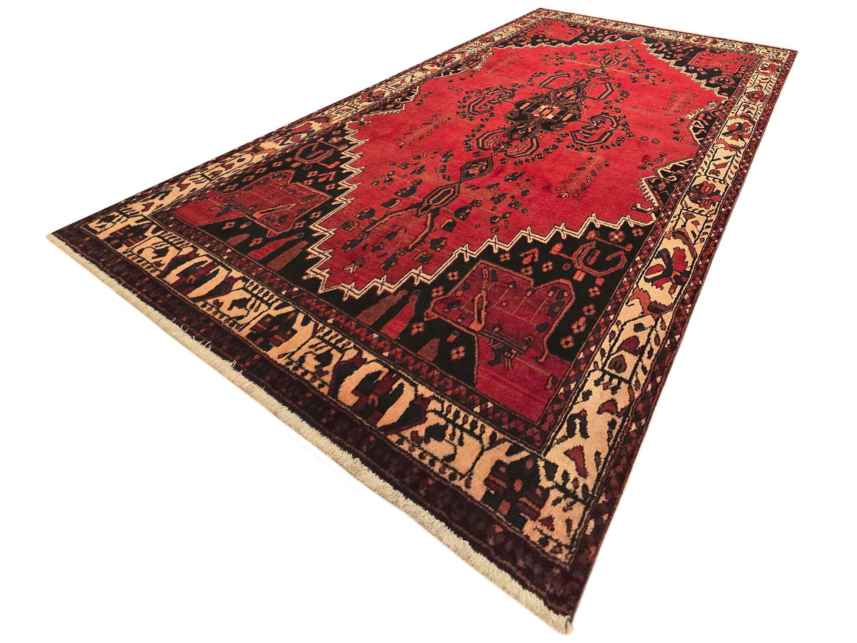 Red patterned rug with central medallion, diamond details, and short cream border fringe