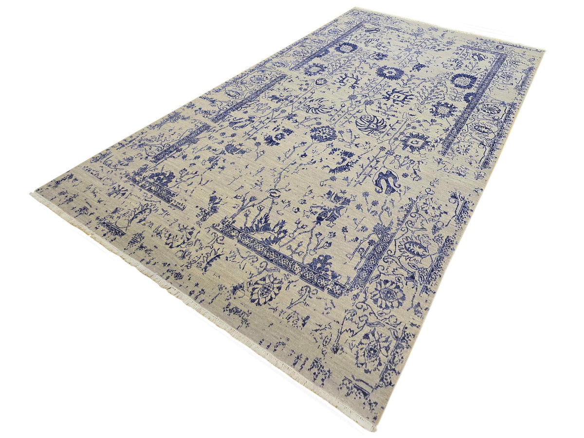 Beige and blue patterned area rug with repeating motifs and trimmed edge, diagonal view.
