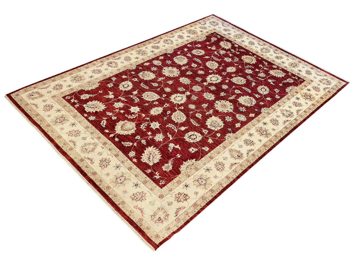 Rectangular red floral area rug with cream border and diamond corner motifs