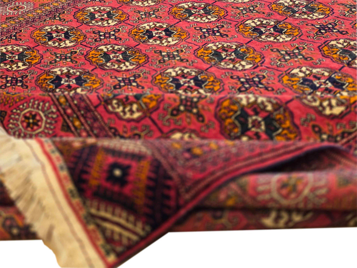 Close-up of red rug with multicolor geometric motifs and border trim detail